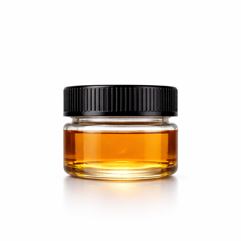 Small clear glass jar with black screw-on lid filled with golden amber CBD CRD distillate, photographed on a clean white background